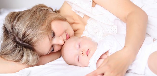 foto de uma mãe deitada junto com o bebe