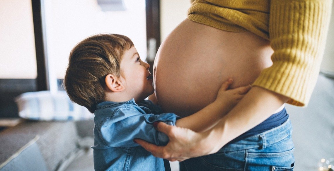 foto de uma criança beijando a barriga gravida da mãe